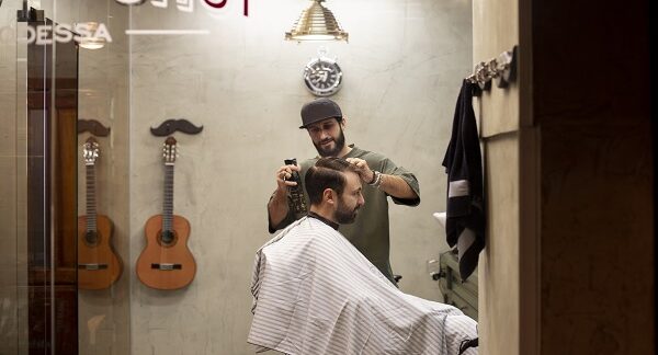 en una de las mejores barberías, un barbero le hace un corte de cabello a u hombre