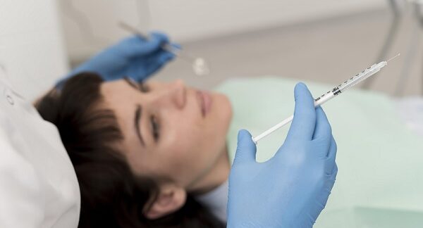 en las mejores clínicas de Botox, un especilista tiene una inyeccion de botox preparada para administrársela a paciente recostada en camilla