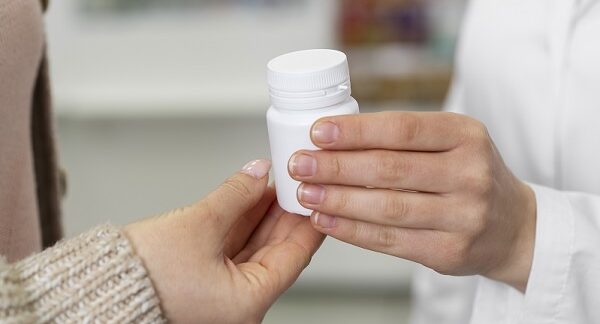 una de las mejores farmacias homeopáticas, un farmacéutico le entrega un frasco de capsulas sin etiqueta, lo que sugiere que son homeopáticas a paciente