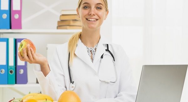 mejores nutricionistas - una de las mejores nutricionistas, sostiene una manzana mientras sonríe