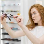 en una de las mejores ópticas, una mujer toma una lentes, revisándolos
