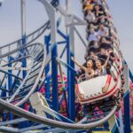 en uno de los parques de atracciones, un serie de personas disfrutando en una montaña rusa