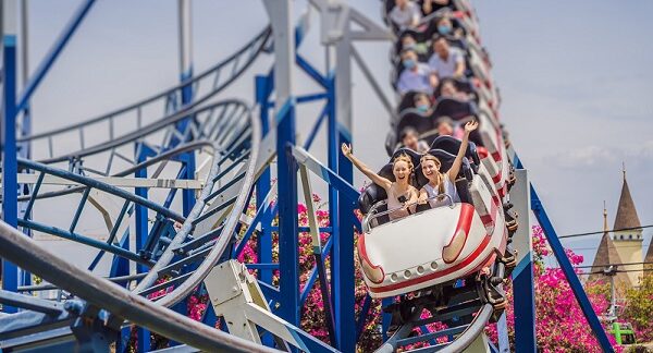 en uno de los parques de atracciones, un serie de personas disfrutando en una montaña rusa
