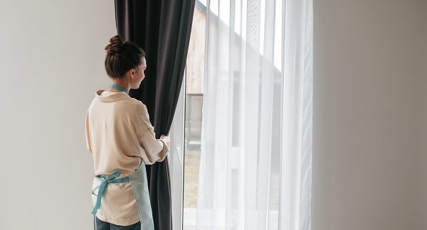 de los servicios de lavado de cortinas, una trabajadora recoge las cortinas para limpiarlas posteriormente