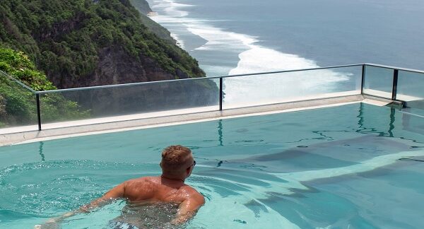 hoteles con piscina climatizada - hombre disfruta de una piscina en el exterior, con vistas al mar