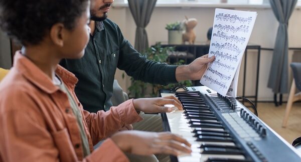 mejores negocios de clases de música - un profesor de música enseña a un alumno a leer partituras de teclado